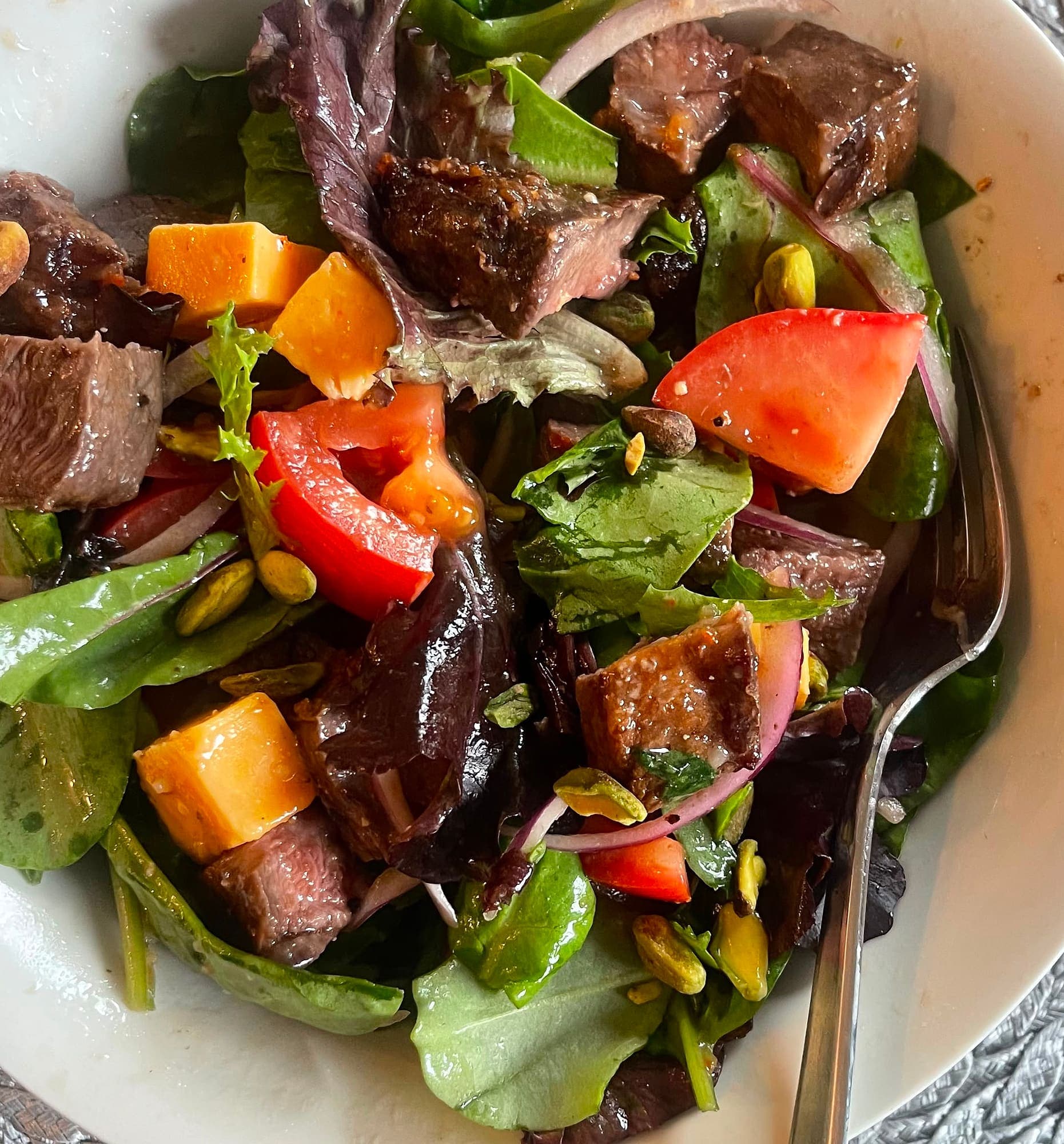 A steak salad with mixed greens, tomato, cheddar and pistachios, cooked in the kitchen at Abbey Road Care Homes